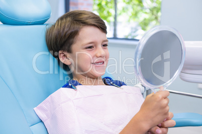 Cute boy looking at mirror while sitting on chair