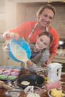Mother and daughter preparing cup cake in kitchen