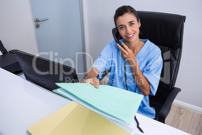 Portrait of doctor holding file while talking on phone