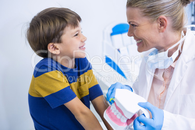 Happy dentist holding dental mold while looking at boy