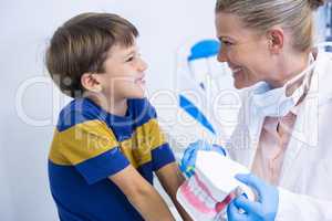Happy dentist holding dental mold while looking at boy