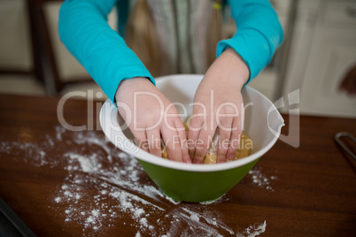 Girl kneading dough in kitchen