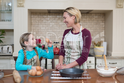 Smiling mother and daughter standing in the kitchen