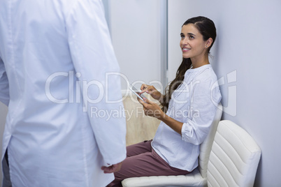 Woman holding tablet while looking at dentist