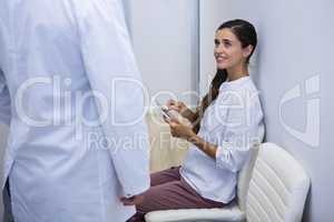 Woman holding tablet while looking at dentist
