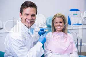 Portrait of doctor holding dental mold while sitting by patient