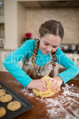 Girl kneading dough in kitchen