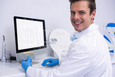 Portrait of dentist working on computer against wall