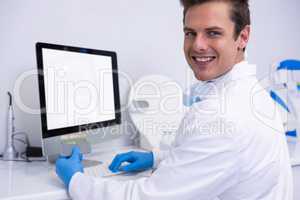 Portrait of dentist working on computer against wall