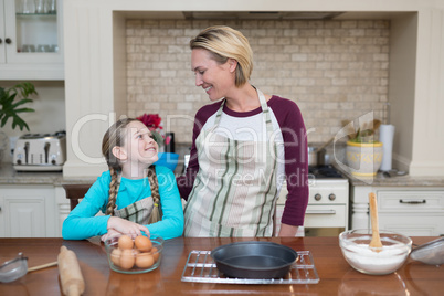 Smiling mother and daughter standing in the kitchen