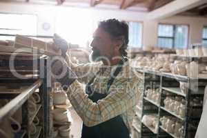 Male potter placing craft product on shelf