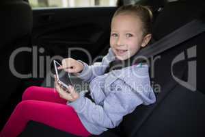 Teenage girl using digital tablet in the back seat of car