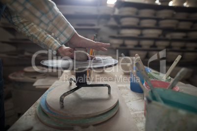 Male potter molding a clay on pottery wheel