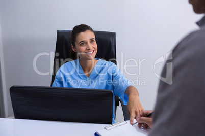 Smiling doctor interacting with patient at desk