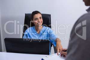 Smiling doctor interacting with patient at desk