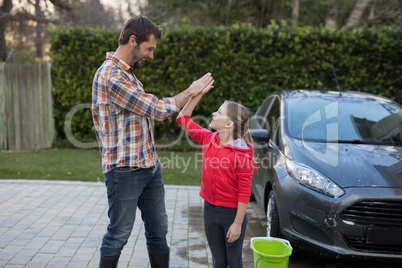 Young girl and father giving high five to each other