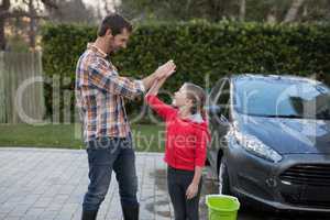Young girl and father giving high five to each other