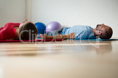 Instructor and student exercising while lying on mat in studio