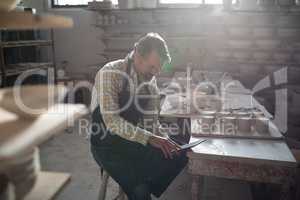 Male potter using digital tablet at worktop