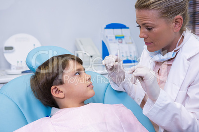 Dentist holding medical equipment while talking to boy