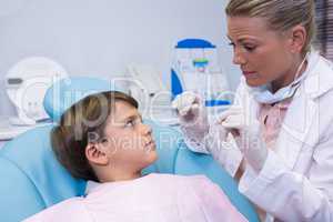 Dentist holding medical equipment while talking to boy