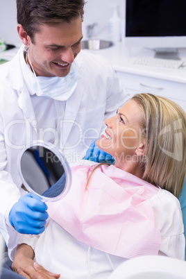 Dentist showing mirror to happy patient