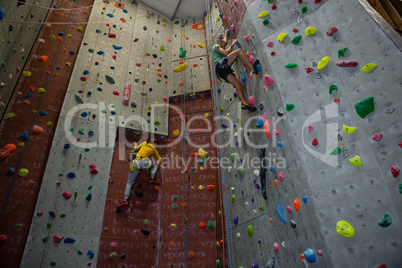 Athletes practicing rock climbing in health club