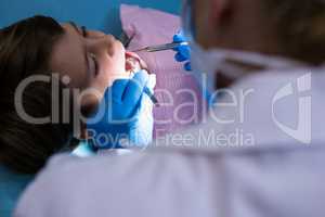 Doctor holding medical equipment while examining boy