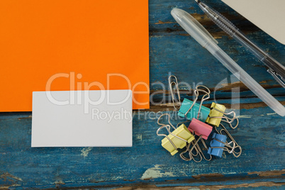 Book, paper clip, visiting cards and blank paper on wooden plank