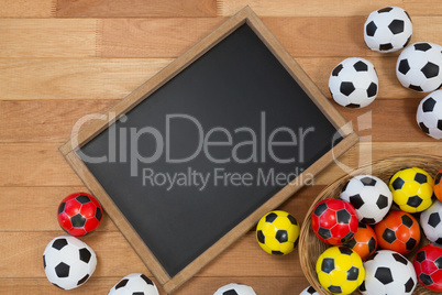 Colorful footballs and slate on wooden table