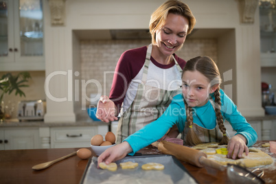 Mother and daughter preparing cookies in kitchen