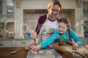 Mother and daughter preparing cookies in kitchen