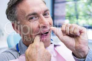 Portrait of man cleaning teeth with string