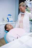 Man lying on dentist chair while doctor standing at clinic