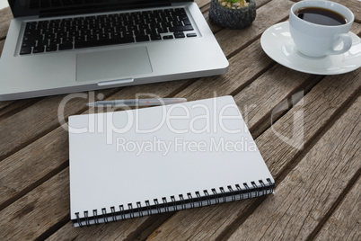 Laptop, notepad and coffee on wooden plank