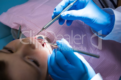 Dentist holding medical equipment while examining cute boy