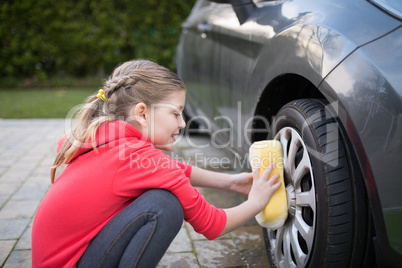 Teenage girl washing a car on a sunny day