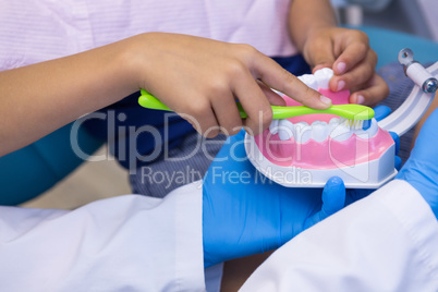 Close-up of dentist and boy brushing dentures