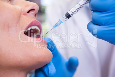 Dentist holding syringe by patient at medical clinic