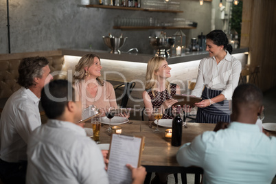 Group of friends giving order to waitress