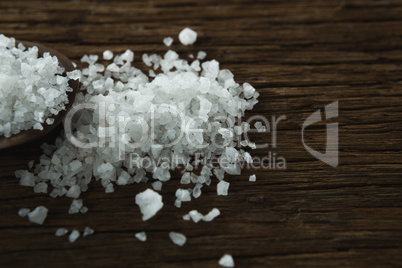 Salt in spoon on wooden table