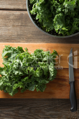 Fresh kale with knife on cutting board