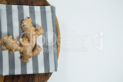 Overhead view of fresh ginger on striped napkin in plate