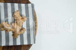 Overhead view of fresh ginger on striped napkin in plate