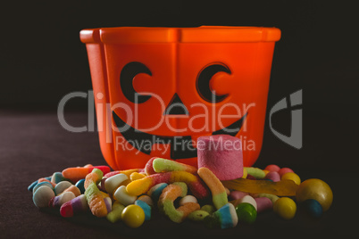 Orange bucket with various candies over black background