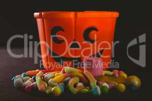 Orange bucket with various candies over black background