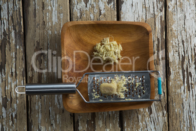 Directly above view of steel grater and ginger in plate on table