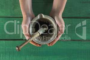 Hand holding herb paste in mortar and pestle