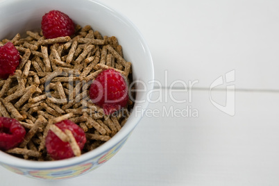 Bowl of cereal bran stick and raspberries
