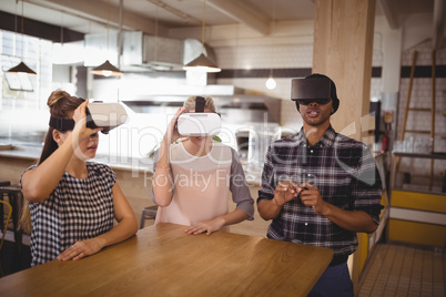Young friends sitting with virtual reality headsets at coffee shop